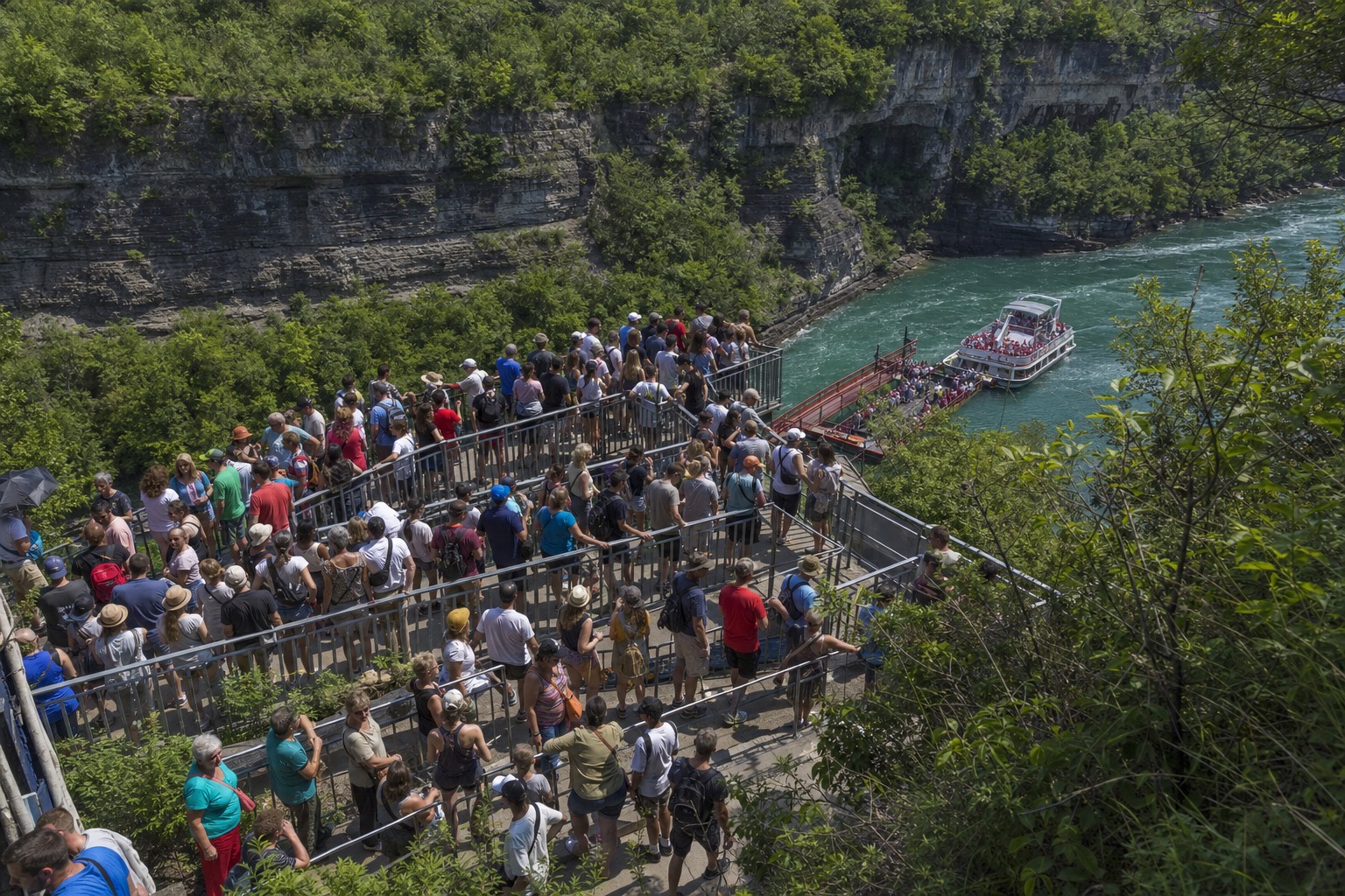 A packed switchback queue of visitors waiting above the Niagara boat landing at midday