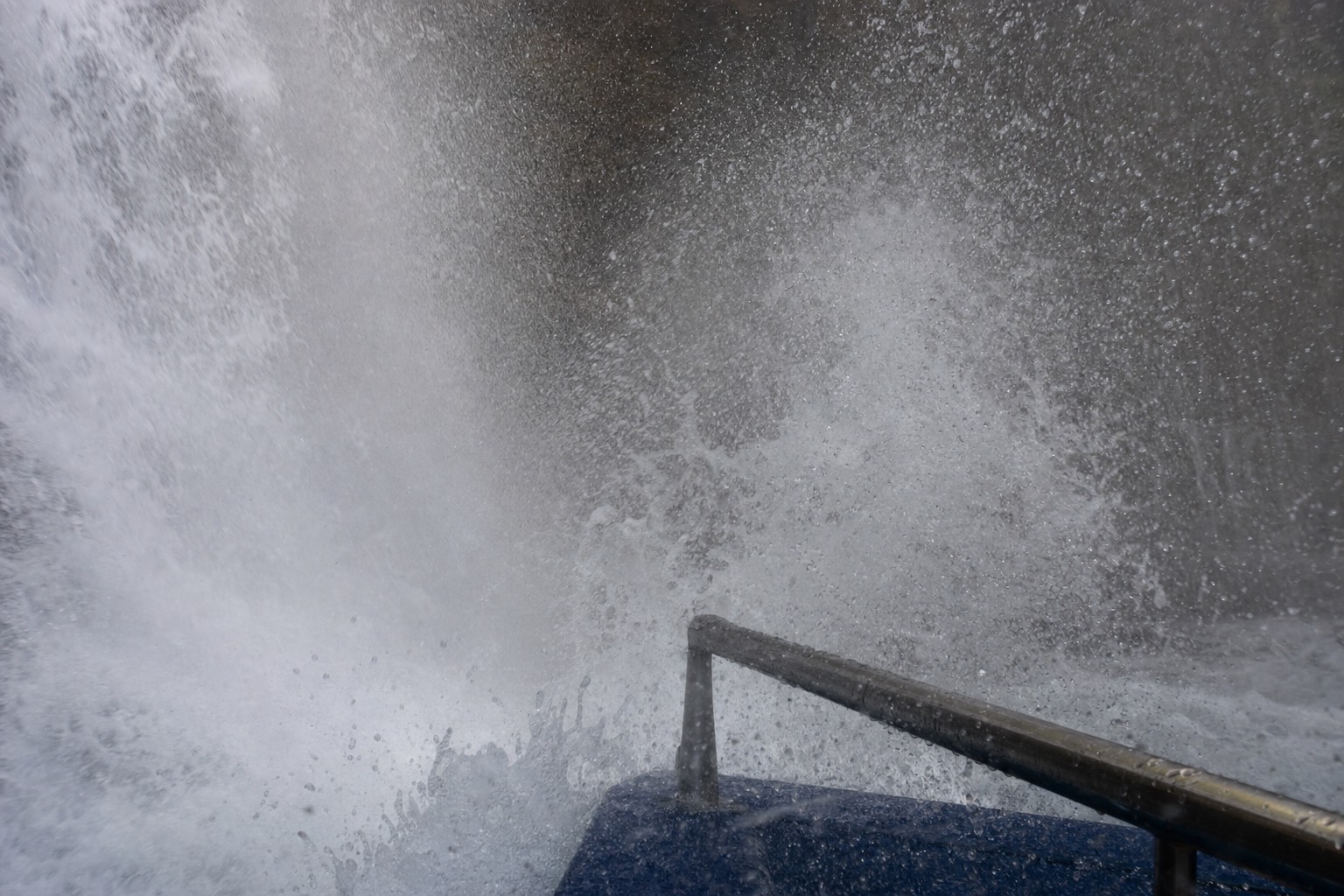 Spray filling the frame at the base of Horseshoe Falls with the boat rail just visible